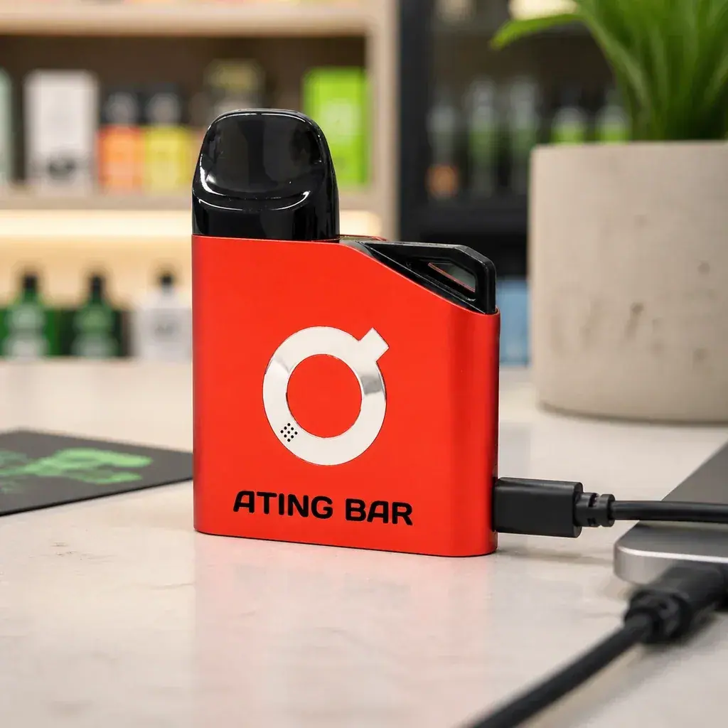 Batería Ating EVO-1 roja con boquilla negra y logotipo plateado, conectada por cable junto a un portátil sobre una mesa.