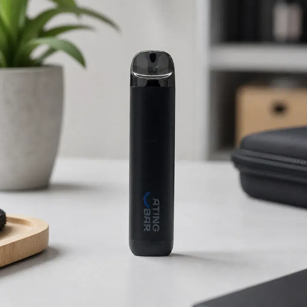 Vape Ating EVO-2 negro en posición vertical sobre una mesa clara, con boquilla oscura translúcida, una maceta y un estuche al fondo.