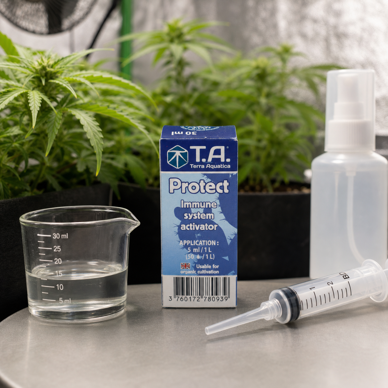Caja de T.A. Protect junto a un vaso graduado con líquido, una jeringa y un pulverizador, con plantas de cannabis al fondo.