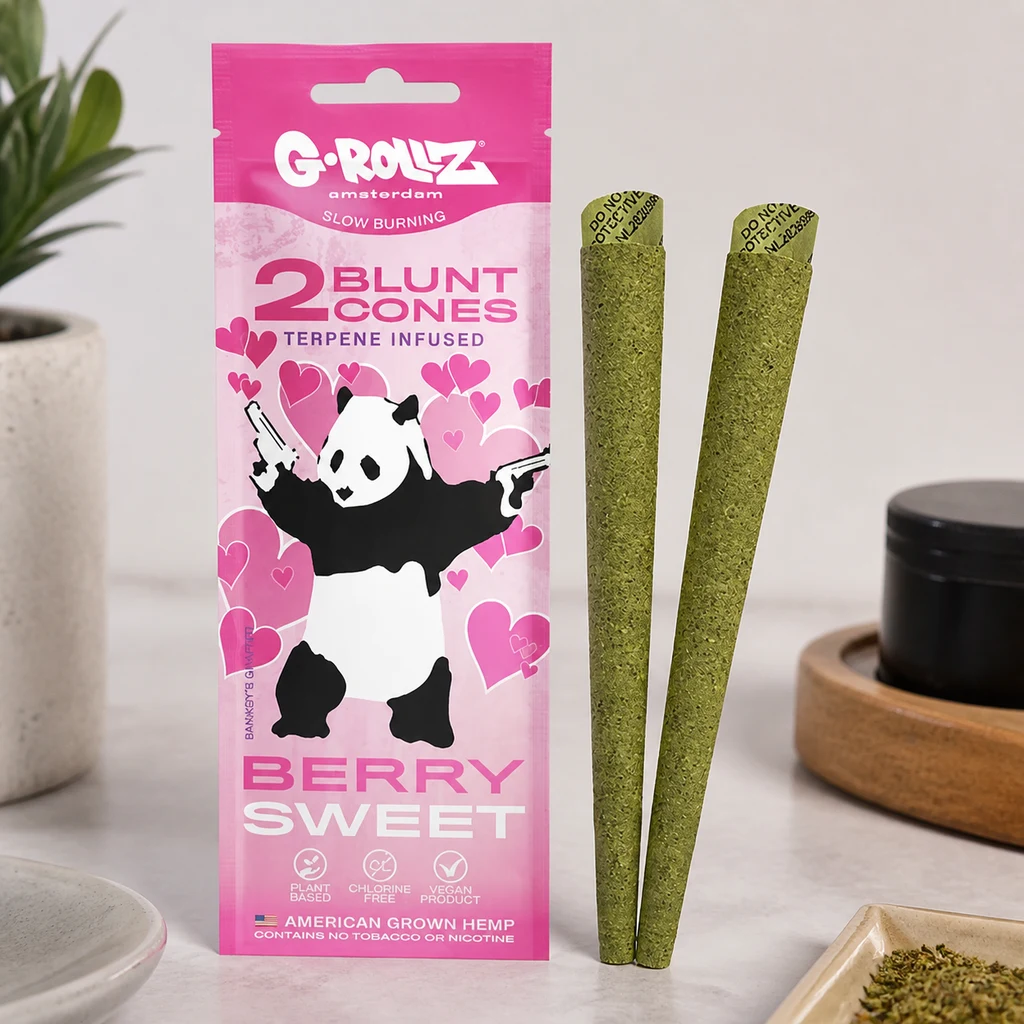 Envase rosa G-Rollz Berry Sweet con un panda entre corazones, junto a dos conos verdes colocados en vertical sobre una mesa.