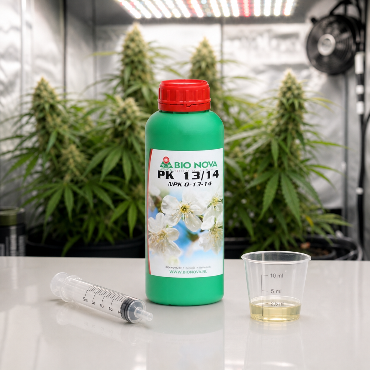 Botella verde de Bio Nova PK 13/14 con tapón rojo, junto a una jeringa y un vaso graduado con líquido, ante plantas de cannabis bajo luces.
