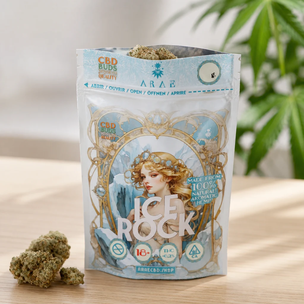 Bolsa Ice Rock abierta, con ilustración de una mujer y adornos azules y dorados, junto a cogollos sobre una mesa de madera.