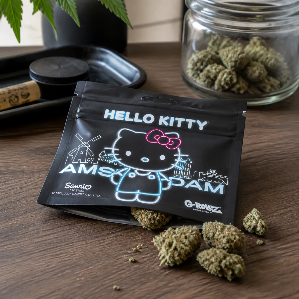 Bolsa negra Hello Kitty con dibujo del personaje y texto Amsterdam, junto a cogollos sobre una mesa y un tarro al fondo.
