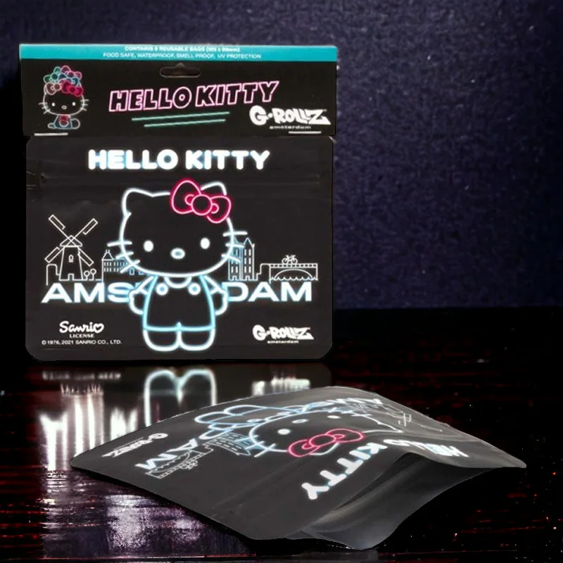 Bolsas negras Hello Kitty de G-Rollz, con dibujos de estilo neón y texto Amsterdam; una en vertical y otra tumbada sobre una mesa.