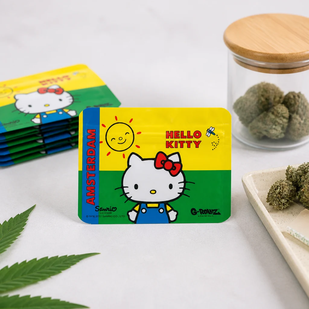 Bolsa Hello Kitty amarilla y verde con franja azul «Amsterdam», junto a varias bolsas apiladas, un tarro y una bandeja con cogollos.
