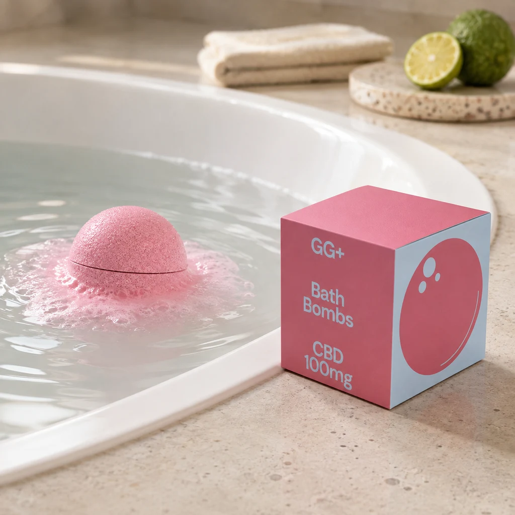 Bomba de baño rosa en agua con espuma junto a una caja GG+ con la inscripción CBD 100 mg, al borde de una bañera.
