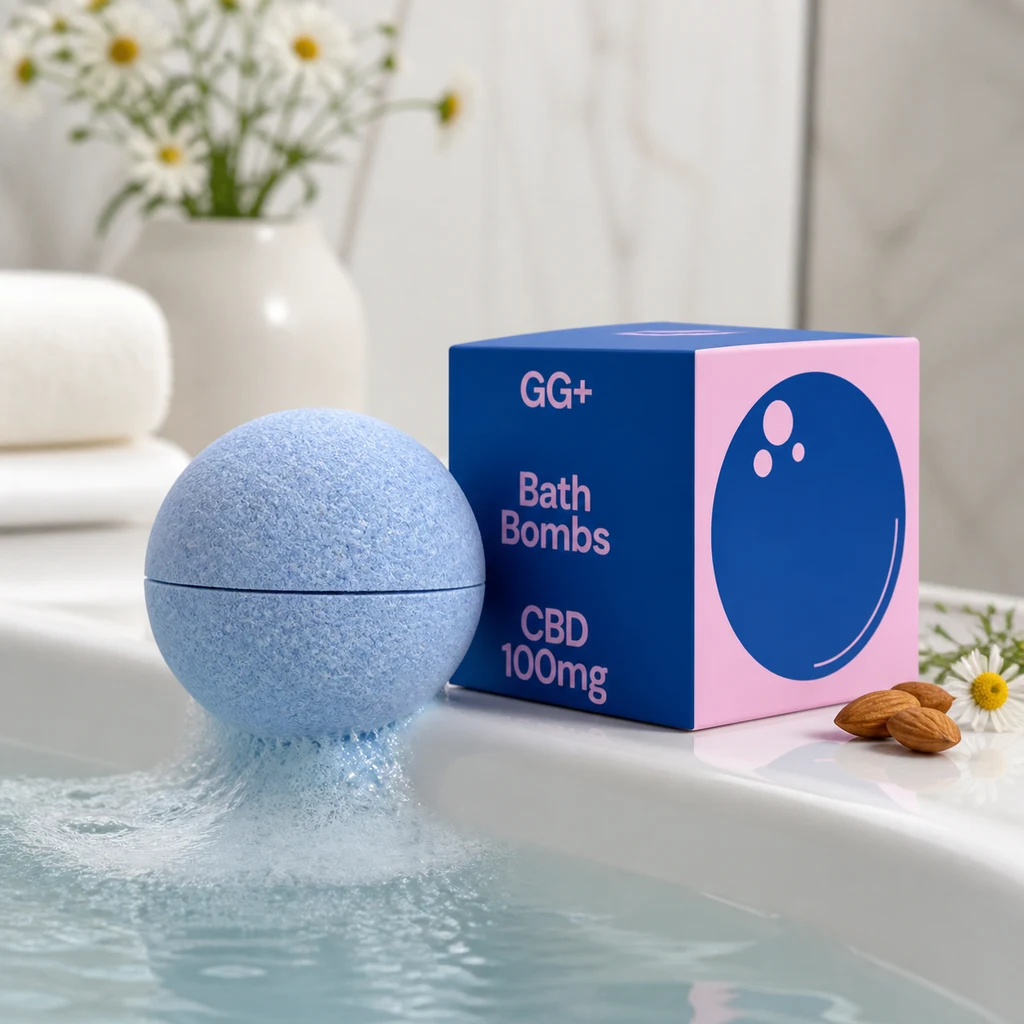 Bomba de baño azul junto al agua y una caja azul y rosa GG+ con el texto «Bath Bombs CBD 100mg», entre flores y almendras.
