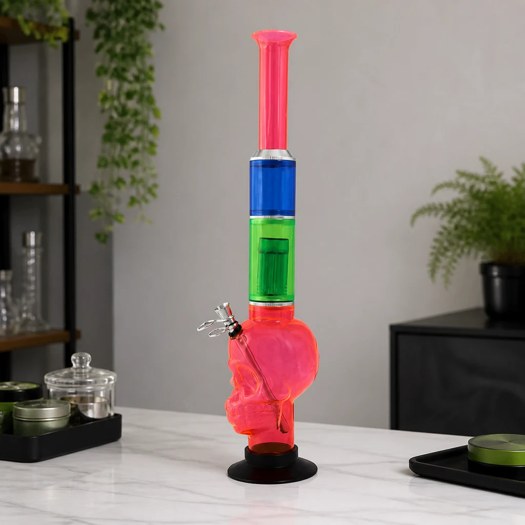 Bong rojo con cámara en forma de calavera, tramos verdes y azules, tubo largo y base negra, sobre una encimera junto a accesorios.