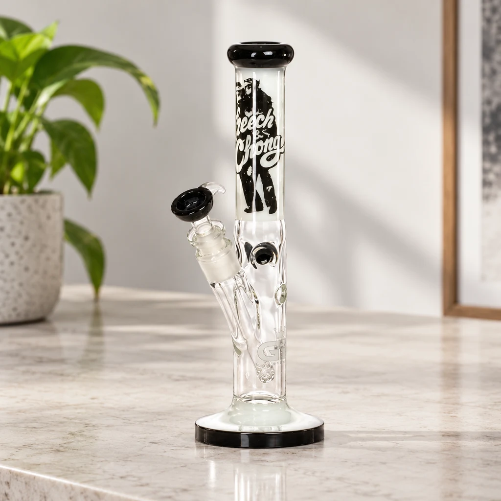 Bong de vidrio Cheech & Chong transparente, con boca y base negras y cazoleta lateral, sobre una encimera junto a una planta.