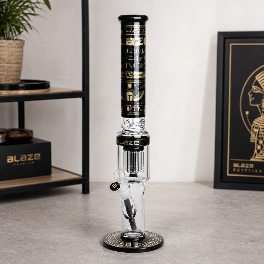 Bong Egyptian Blaze de pie sobre una mesa, con percolador visible, cazoleta lateral y motivos egipcios dorados sobre negro.