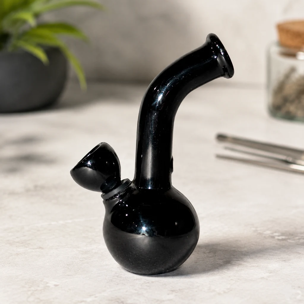 Bong negro brillante con base redondeada, cuello curvado y cazoleta lateral, sobre una superficie clara.