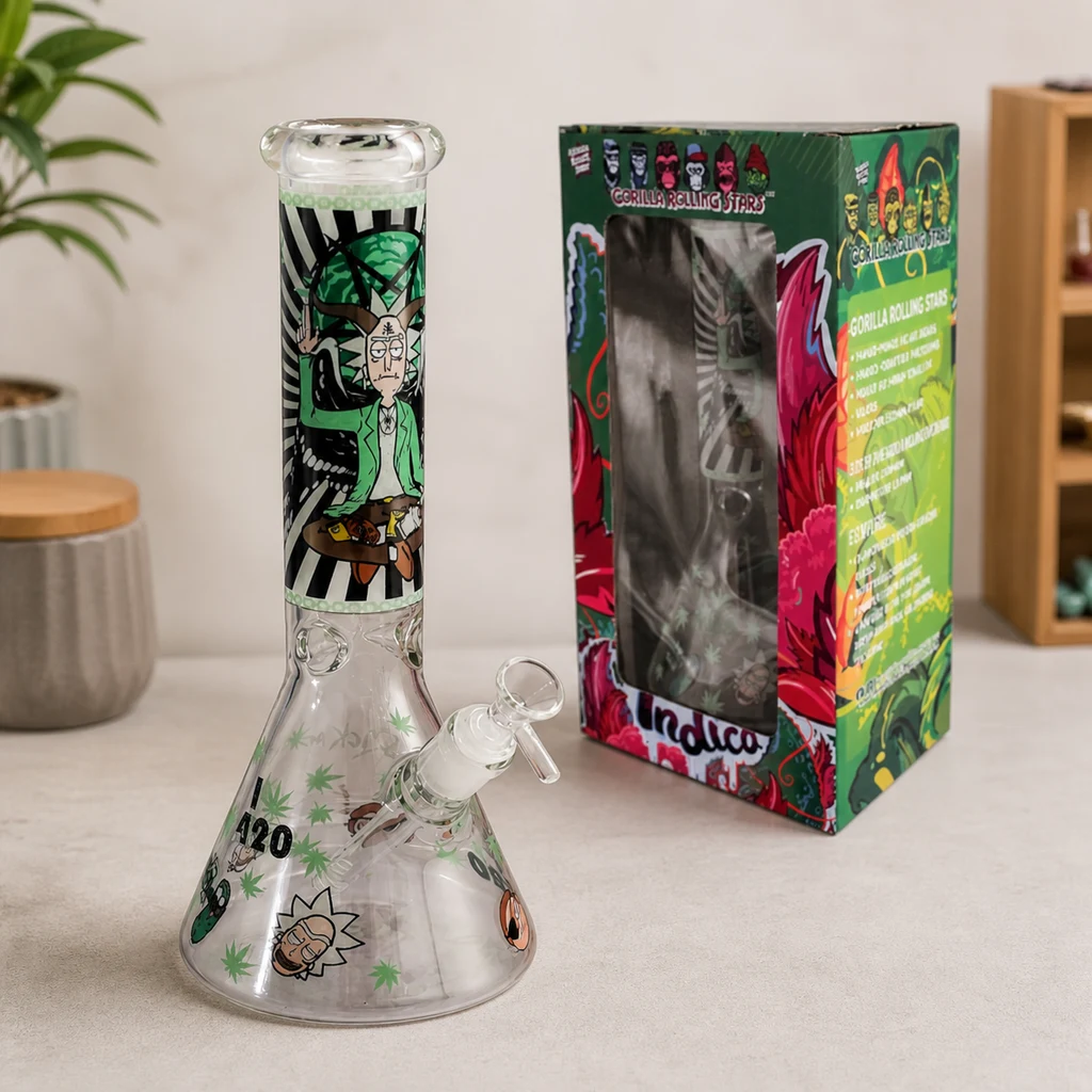 Bong de cristal Rick and Morty con base cónica, tubo alto decorado y cazoleta lateral, junto a una caja de dibujos multicolores.