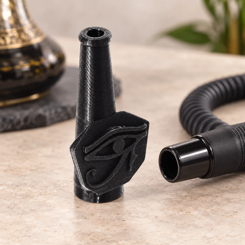 Boquilla Horus 3D negra con relieve del ojo de Horus, junto al extremo de una manguera de cachimba sobre una encimera. Boquilla Horus 3D negra con relieve del ojo de Horus, junto al extremo de una manguera de cachimba sobre una encimera.
