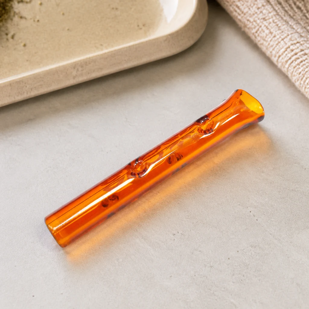 Boquilla de cristal Eko Puffs Twister naranja translúcida, con relieves interiores, colocada en diagonal sobre una superficie clara.