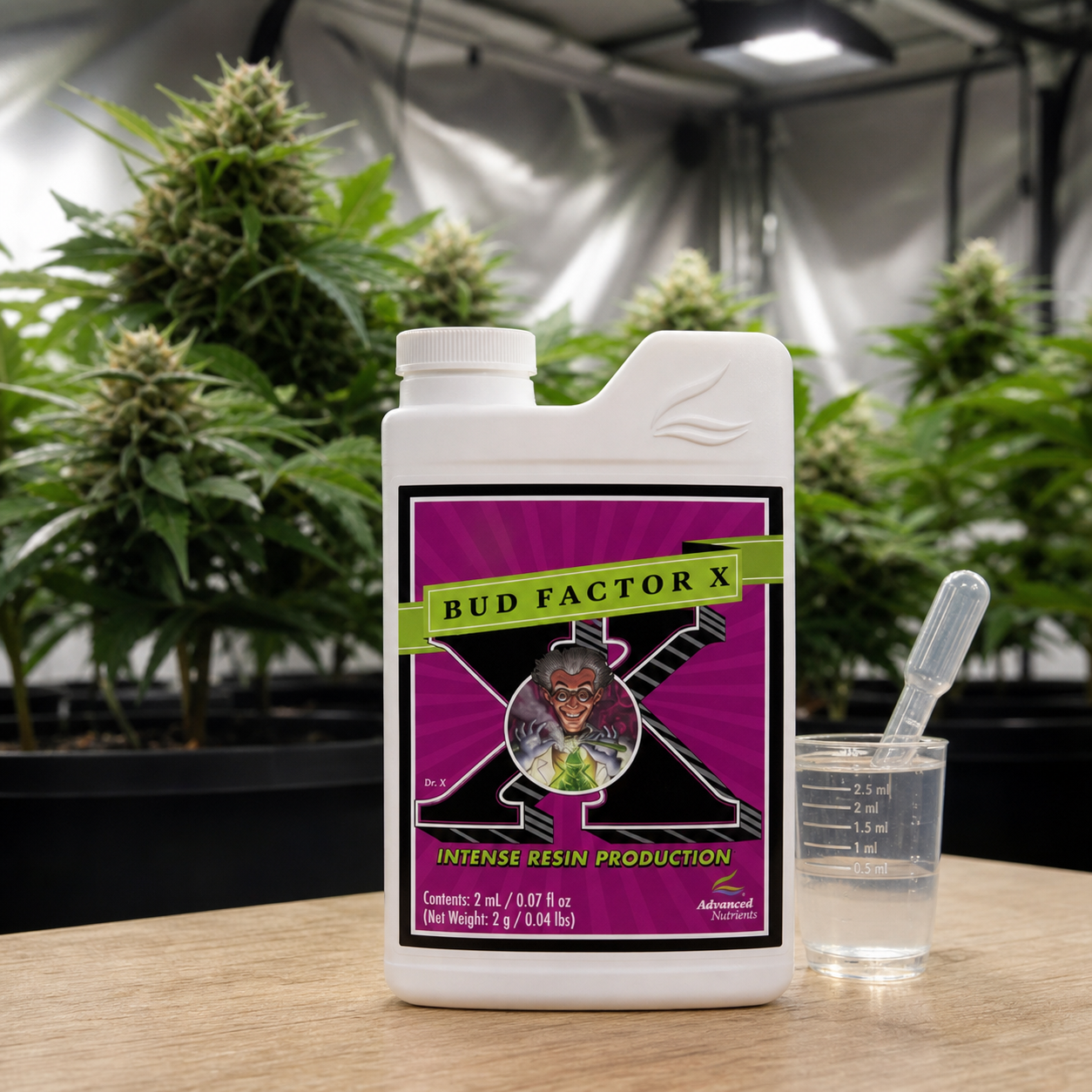 Envase blanco de Bud Factor X Advanced Nutrients sobre una mesa, junto a un vaso graduado y una pipeta, con plantas al fondo.