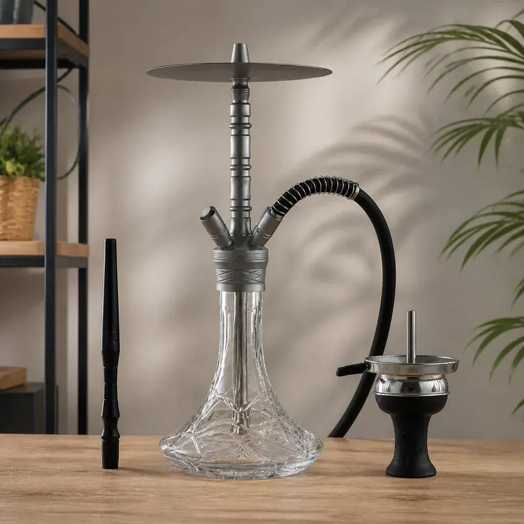 Cachimba Aladin ALU7 con base transparente tallada, mástil gris y manguera negra sobre una mesa, junto a boquilla y cazoleta separadas.