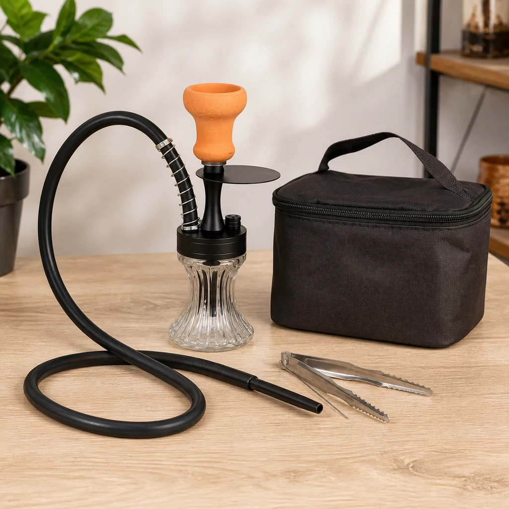 Cachimba mini con base transparente, cuerpo negro y cazoleta naranja, junto a una bolsa de transporte, manguera y pinzas sobre una mesa.