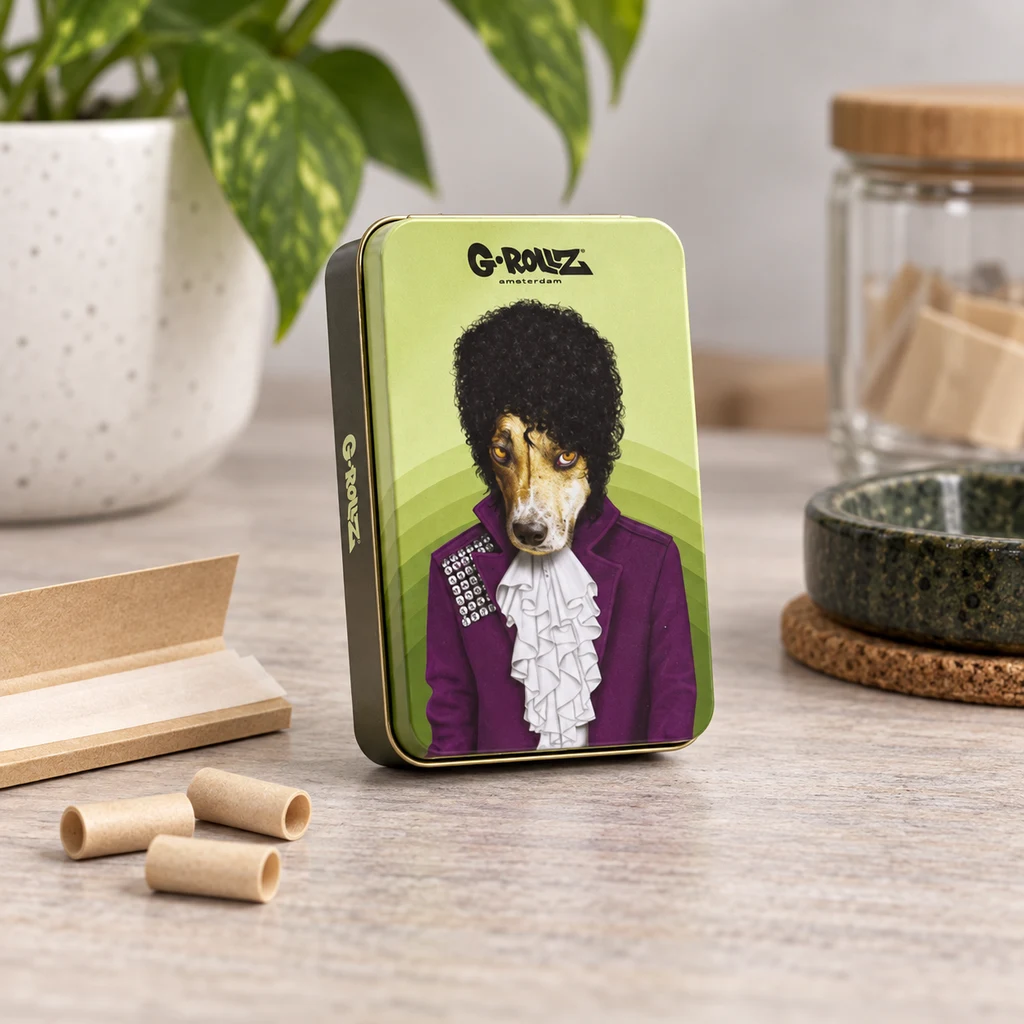 Caja Roxy Icons verde con un perro ilustrado vestido de morado, sobre una mesa junto a papel de liar, boquillas y un cenicero.