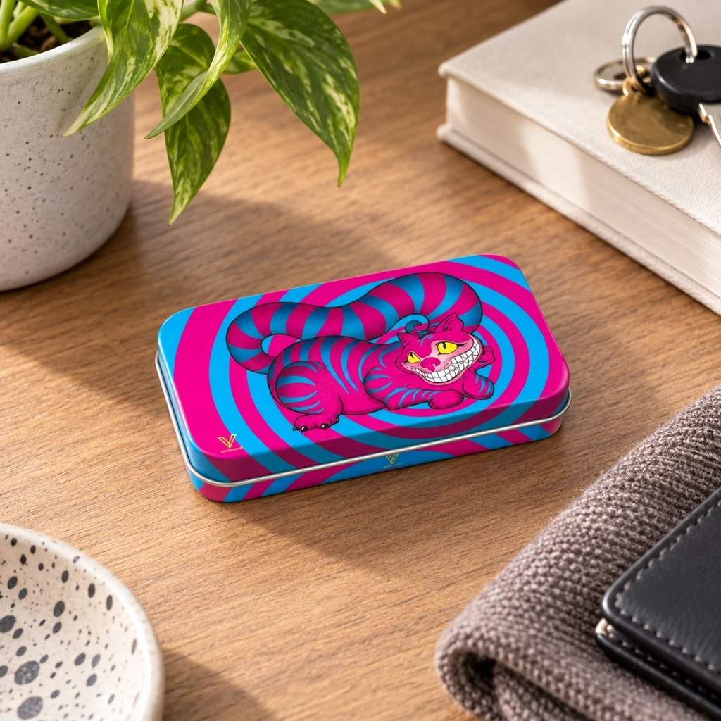 Caja rectangular con un gato sonriente fucsia y espirales turquesas sobre una mesa de madera, junto a una planta, llaves y una cartera.