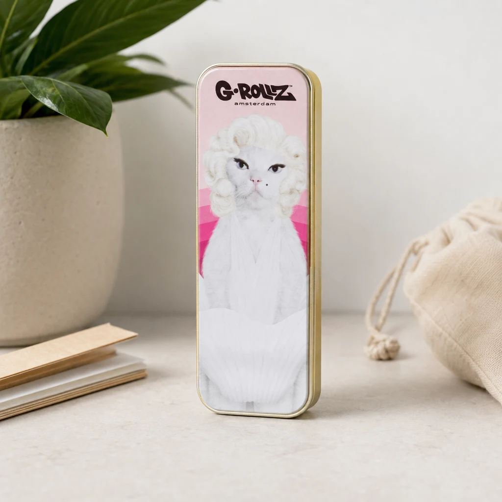 Caja G-Rollz Pet Rocks Cat de pie, con bordes dorados y un gato blanco con peinado rizado sobre fondo rosa, junto a una maceta. Caja G-Rollz Pet Rocks Cat de pie, con bordes dorados y un gato blanco con peinado rizado sobre fondo rosa, junto a una maceta.
