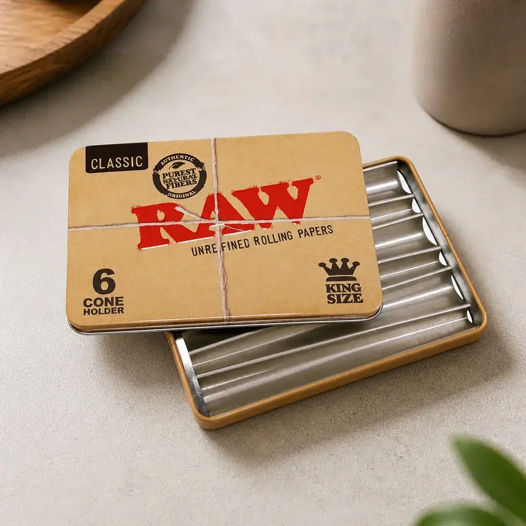 Caja metálica RAW para conos, abierta sobre una mesa clara, con canales interiores y tapa beige con logotipo rojo y texto King Size.