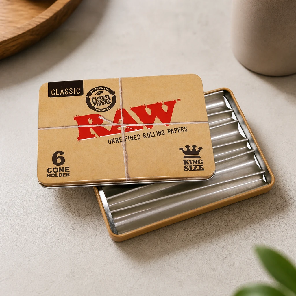 Caja metálica RAW para conos, abierta sobre una mesa clara, con canales interiores y tapa beige con logotipo rojo y texto King Size. Caja metálica RAW para conos, abierta sobre una mesa clara, con canales interiores y tapa beige con logotipo rojo y texto King Size.
