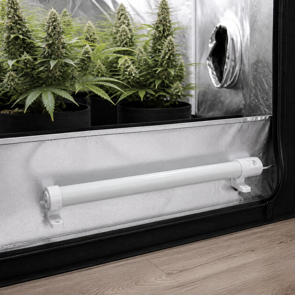 Calentador tubular blanco sobre soportes en la parte baja de un armario de cultivo reflectante, con plantas en macetas al fondo.