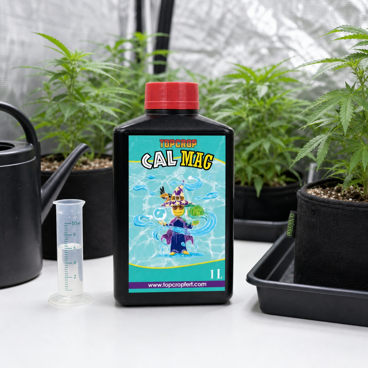 Botella de CalMag Top Crop de 1 L con tapón rojo, junto a una probeta y una regadera, entre plantas en macetas. Botella de CalMag Top Crop de 1 L con tapón rojo, junto a una probeta y una regadera, entre plantas en macetas.