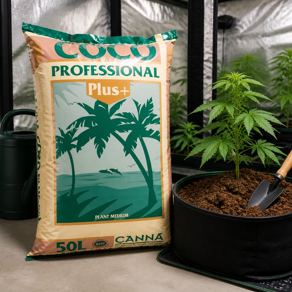 Saco de Canna Coco Professional Plus 50 L junto a una planta en maceta, una pala y una regadera en un espacio de cultivo interior.