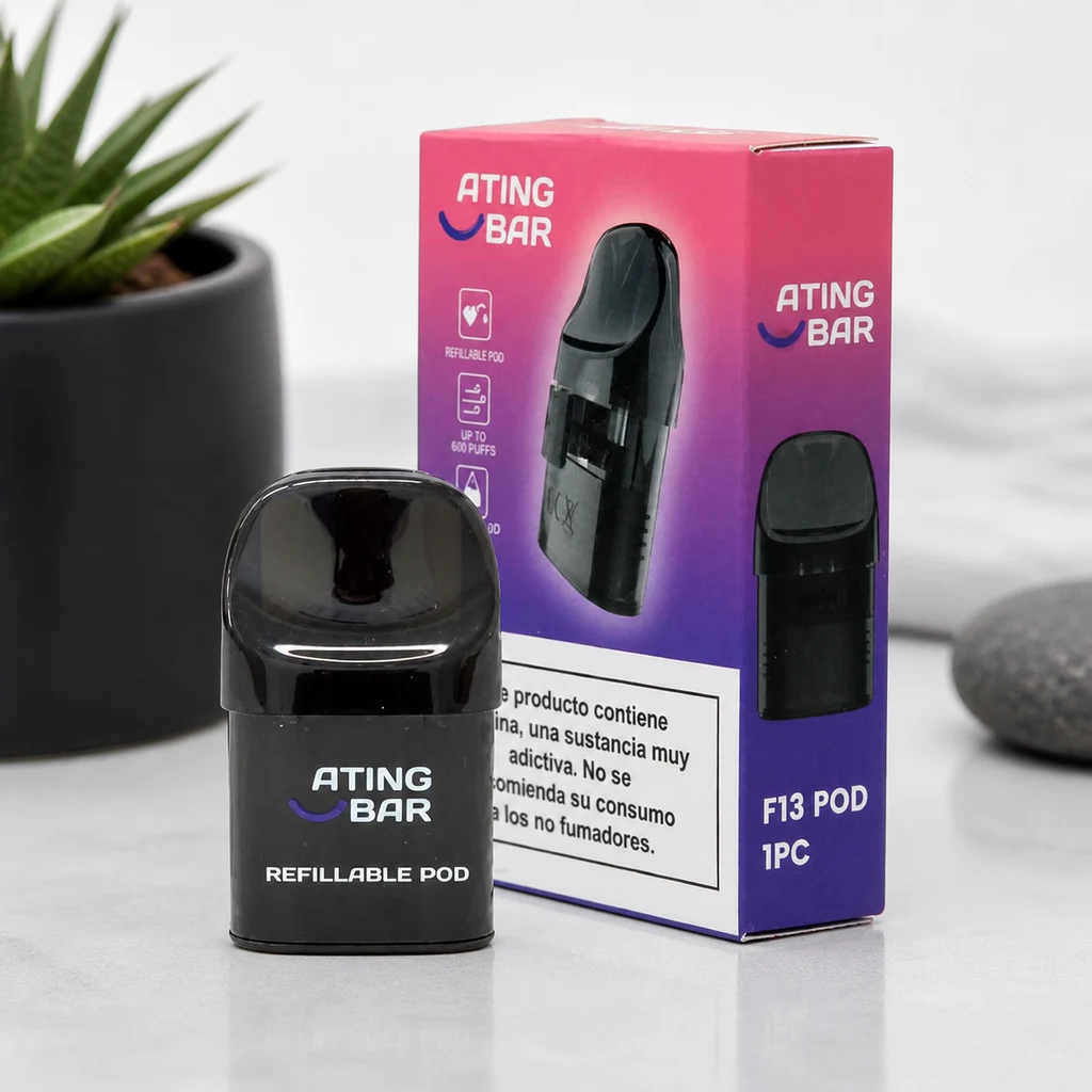 Pod recargable Ating negro con boquilla redondeada, junto a su caja rosa y morada rotulada F13 POD, sobre una superficie clara.