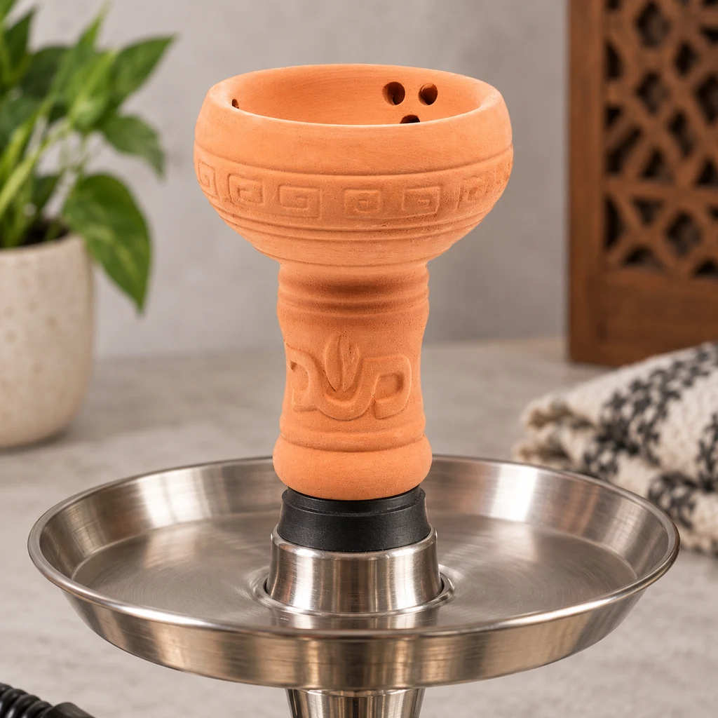 Cazoleta de arcilla naranja con motivos geométricos y orificios interiores, montada sobre el plato metálico de una cachimba.
