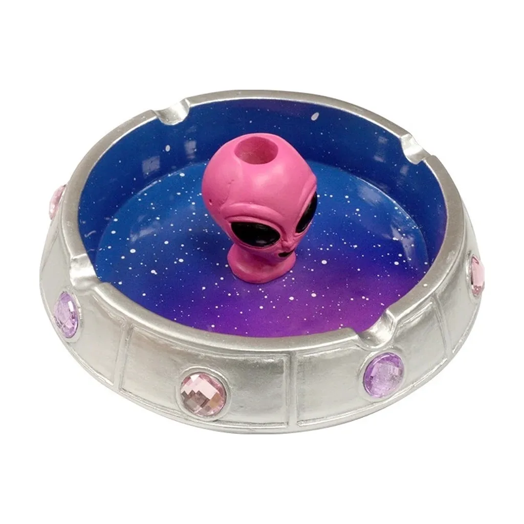 Cenicero circular con borde plateado, adornos rosas y violetas e interior estrellado azul y morado con una cabeza de alien rosa.