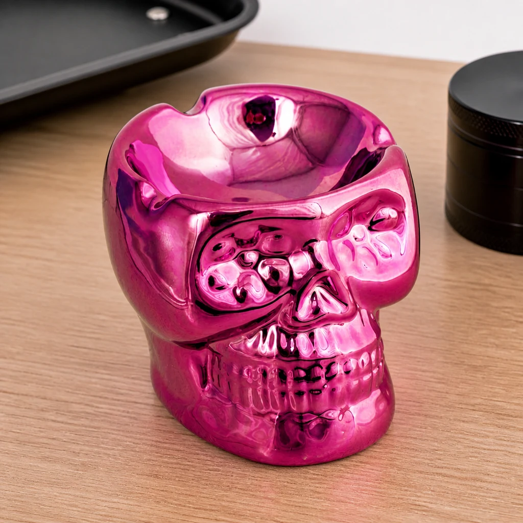 Cenicero rosa brillante con forma de calavera, cuenco superior y muescas en el borde, sobre una mesa de madera.