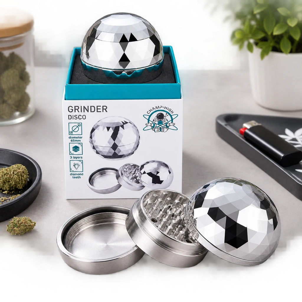 Escena generada del grinder Champ High Disco plateado, abierto y cerrado junto a su caja, con tapa facetada y hierba alrededor.