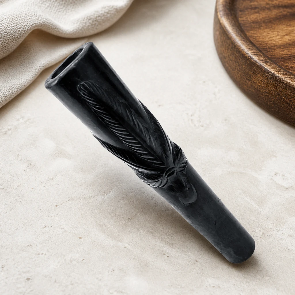 Chillum Leaf negro con una hoja en relieve, colocado en diagonal sobre una superficie clara junto a una bandeja de madera.