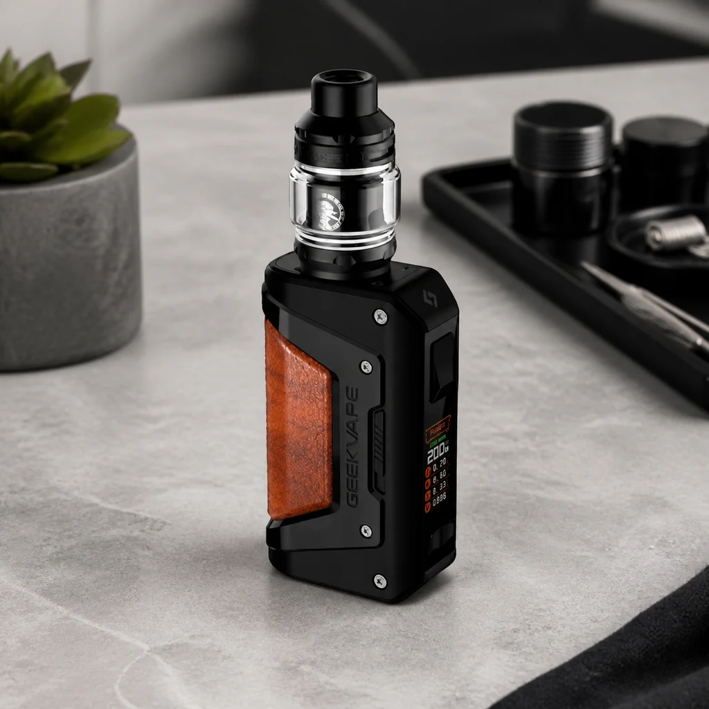 Geekvape Aegis Legend 2 negro con panel marrón, pantalla lateral y depósito transparente, sobre una mesa junto a accesorios. Geekvape Aegis Legend 2 negro con panel marrón, pantalla lateral y depósito transparente, sobre una mesa junto a accesorios.