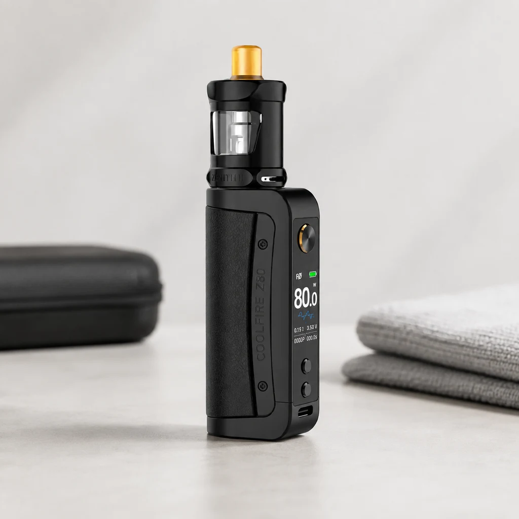 Kit Innokin Coolfire Z80 negro con depósito transparente, boquilla dorada y pantalla encendida, sobre una mesa junto a un estuche y toallas.