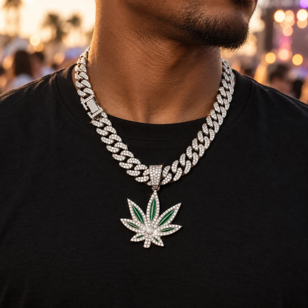 Primer plano de un collar de eslabones plateados con colgante de hoja de cannabis verde y piedras brillantes sobre una camiseta negra.
