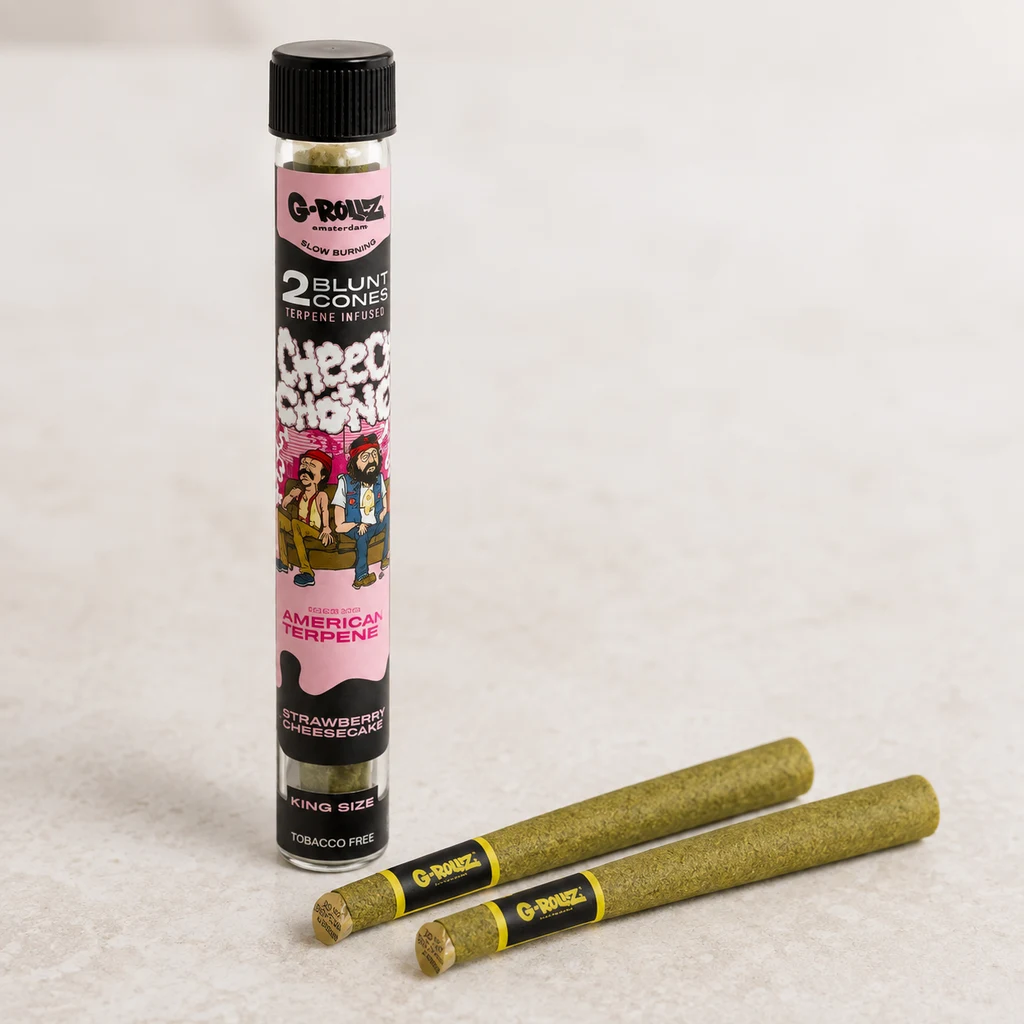 Conos para blunt G-Rollz junto a un tubo con tapón negro y etiqueta rosa de Cheech & Chong que indica Strawberry Cheesecake. Conos para blunt G-Rollz junto a un tubo con tapón negro y etiqueta rosa de Cheech & Chong que indica Strawberry Cheesecake.