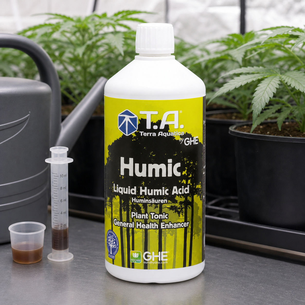Botella de Terra Aquatica Humic con etiqueta amarilla y negra, junto a una jeringa dosificadora, un vasito con líquido y una regadera. Botella de Terra Aquatica Humic con etiqueta amarilla y negra, junto a una jeringa dosificadora, un vasito con líquido y una regadera.