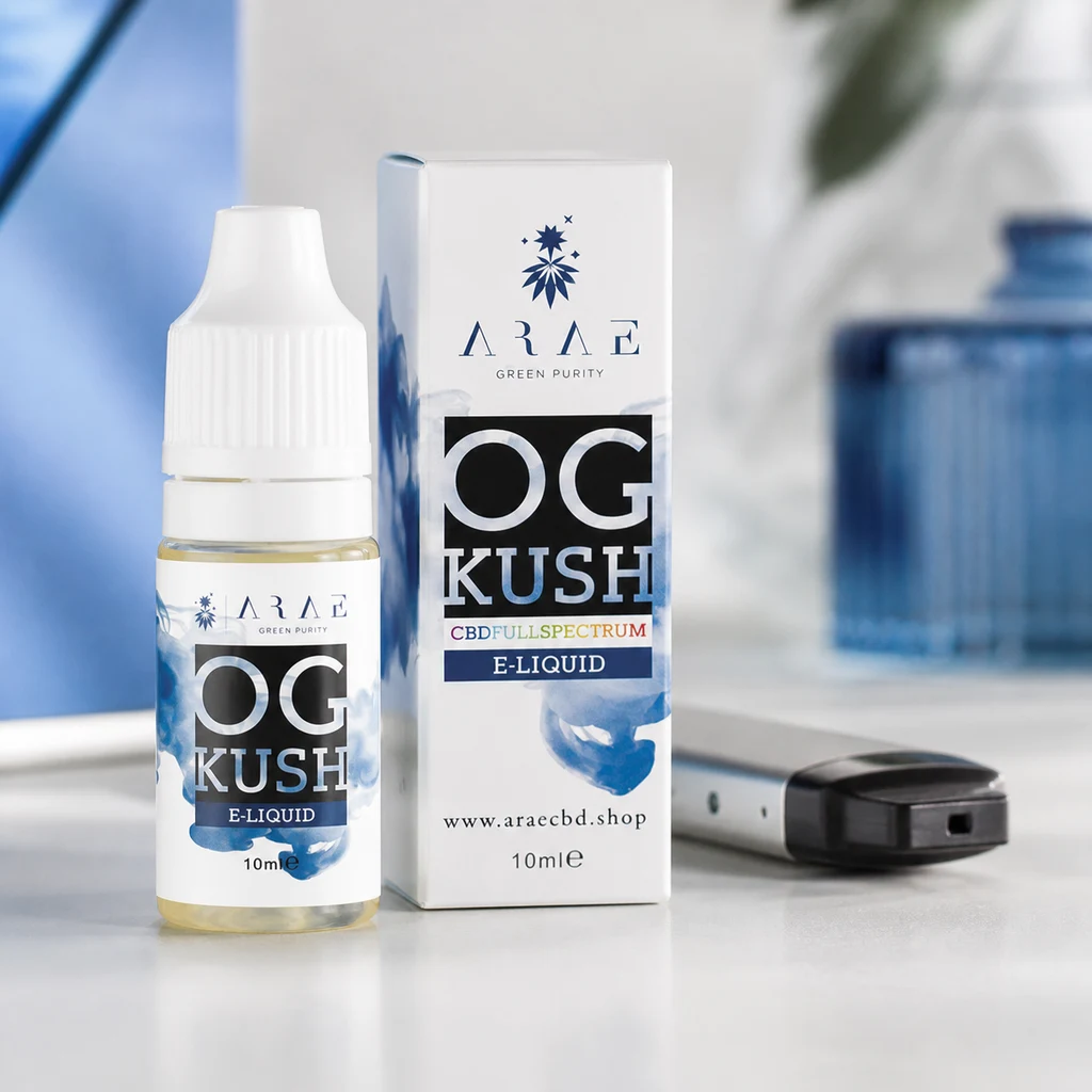 Frasco ARAE OG Kush E-Liquid de 10 ml junto a su caja blanca con detalles azules y un dispositivo de vapeo tumbado sobre la mesa.