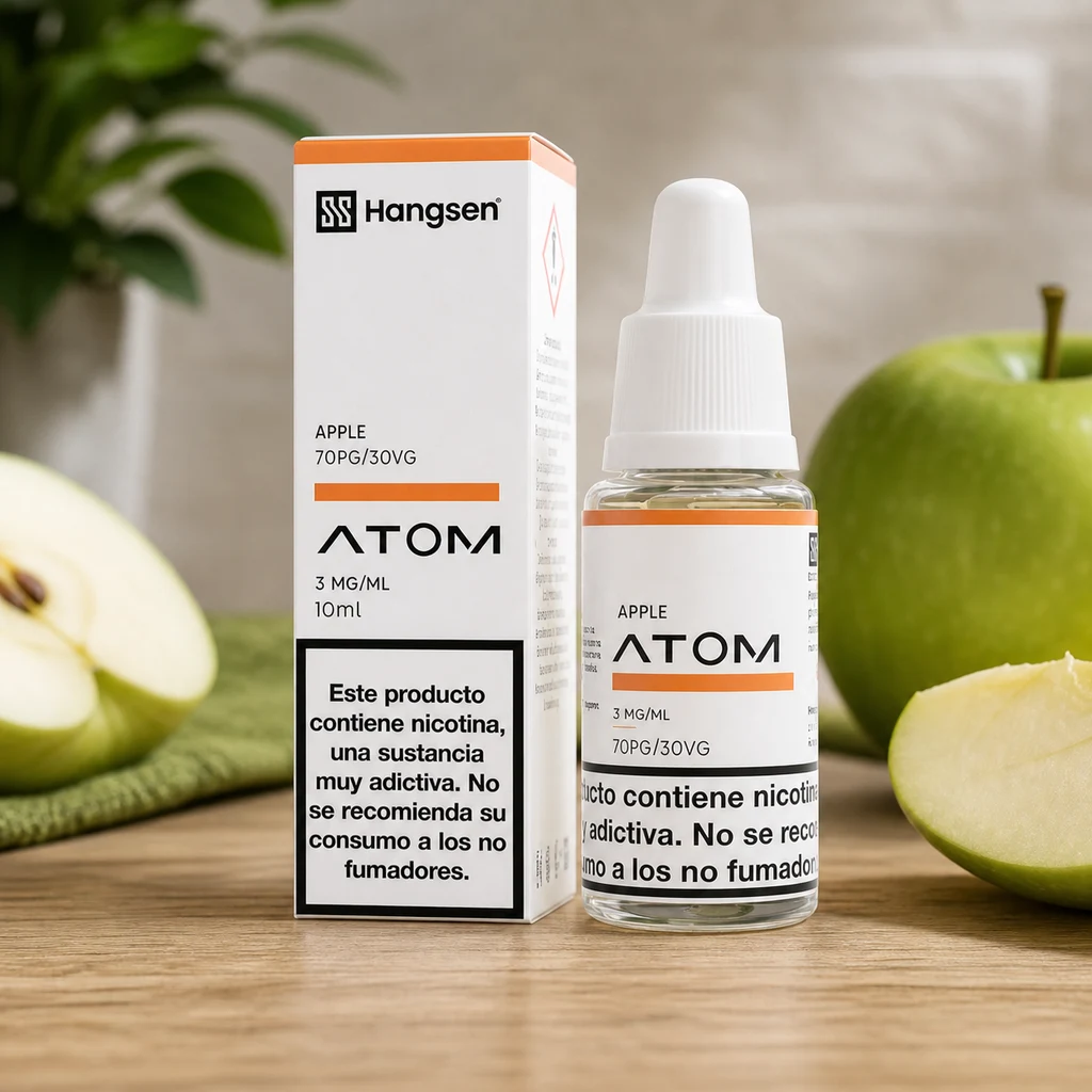 Frasco de e-líquido Apple Hangsen Atom junto a su caja blanca y naranja, con manzanas verdes enteras y cortadas sobre una mesa.