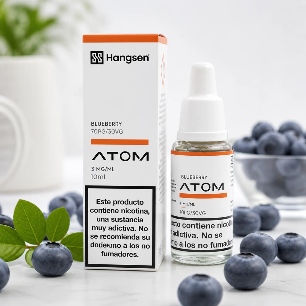 Frasco de e-líquido Hangsen Atom Blueberry con su caja blanca y naranja, rodeado de arándanos sobre una superficie clara.