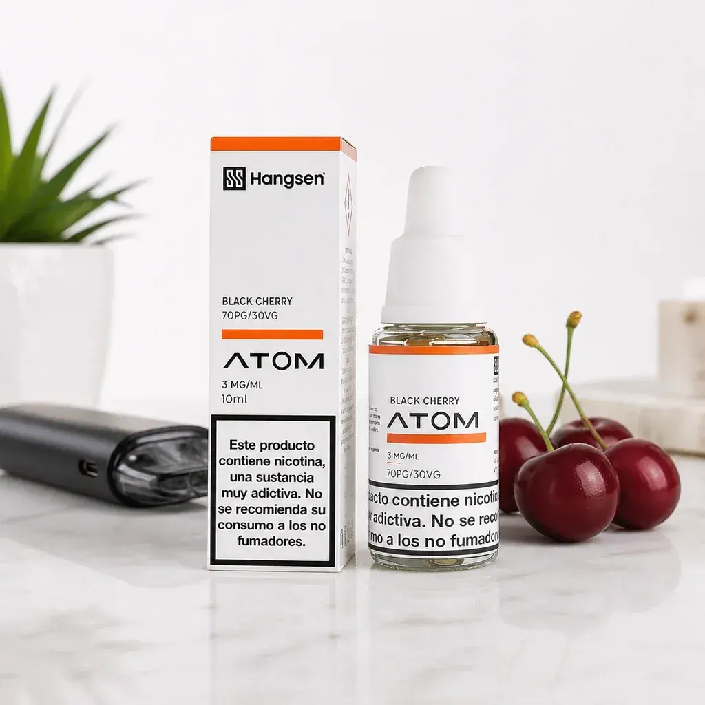 Frasco y caja Hangsen Atom Black Cherry con etiquetas de 10 ml, junto a cerezas y un dispositivo de vapeo.