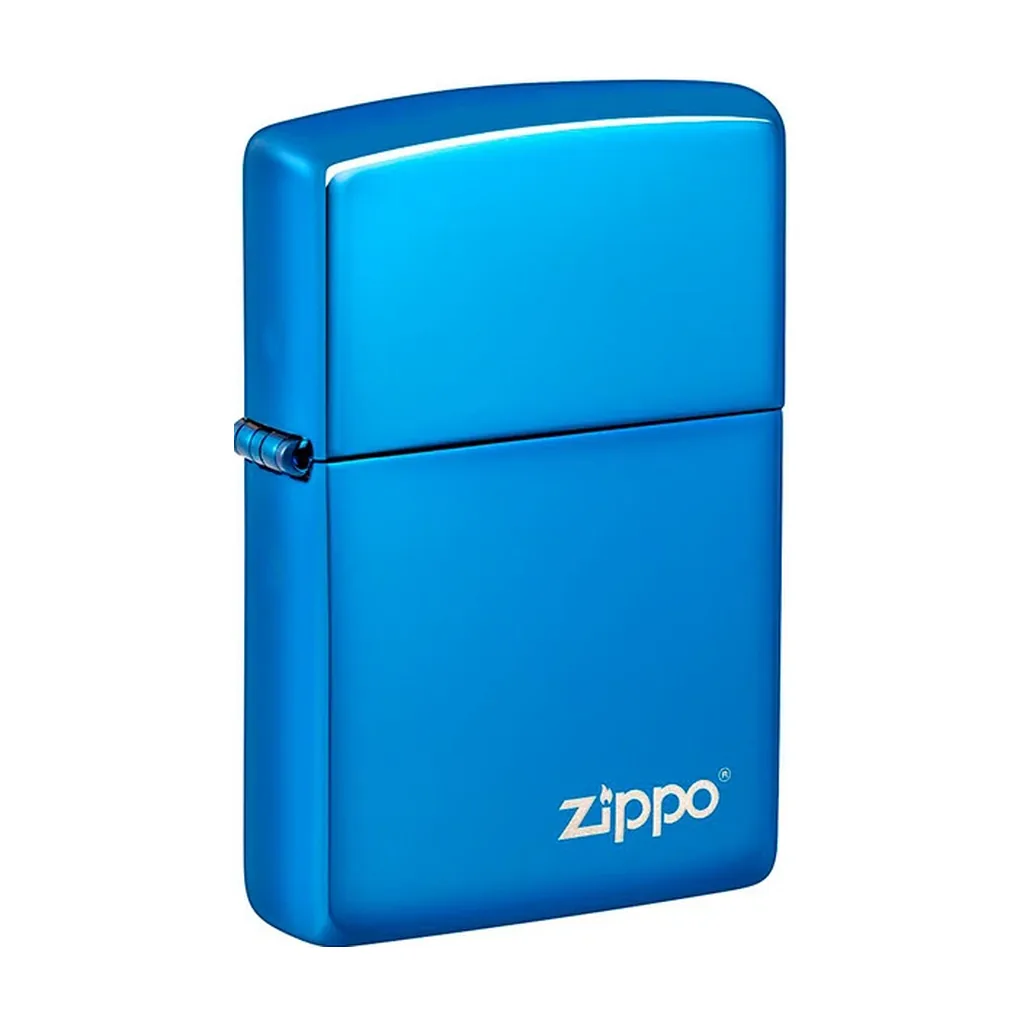 Encendedor Zippo azul brillante, cerrado y visto ligeramente de lado, con bisagra lateral y logotipo plateado en la parte inferior.
