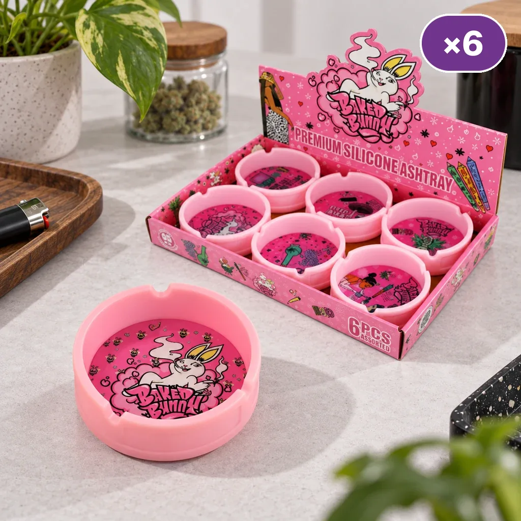 Cenicero rosa Baked Bunny con un conejo ilustrado, sobre una encimera junto a un expositor con varias unidades de distintos dibujos.
