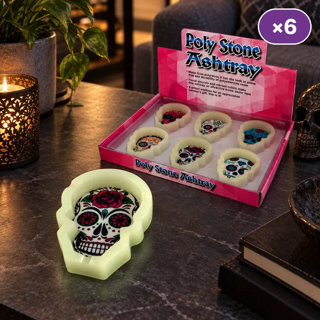 Escena generada con un cenicero claro en forma de calavera decorada y una caja expositora con varios modelos sobre una mesa.