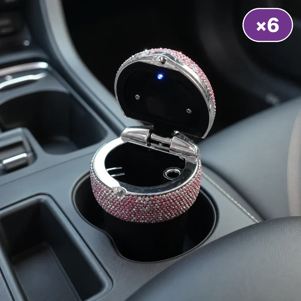 Cenicero brillante rosa y plateado abierto en el portavasos de un coche, con luz azul bajo la tapa y distintivo ×6.