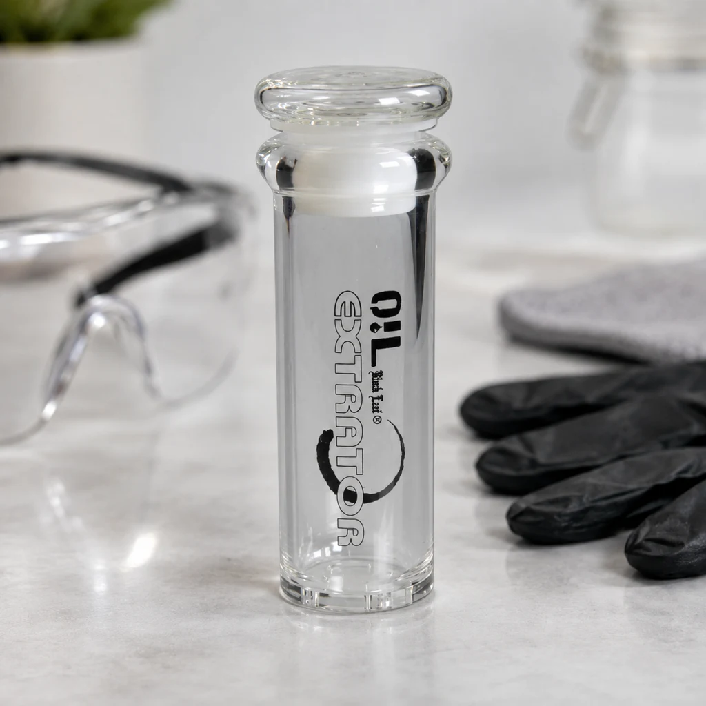 Extractor BHO Black Leaf transparente, de forma cilíndrica y con inscripción negra, sobre una mesa junto a gafas protectoras y guantes negros.