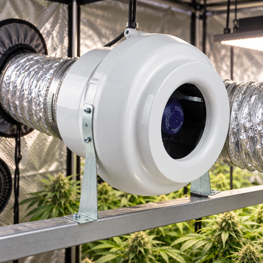 Extractor Tubular VK blanco conectado a conductos plateados y sujeto con soportes metálicos dentro de un armario de cultivo con plantas.